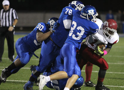 Hunter Fugitt (33), Cameron Murray (76) and Mario Waits (90) put the clamps on Texarkana running back Stacy Moss. (Photo by Rick Nation)