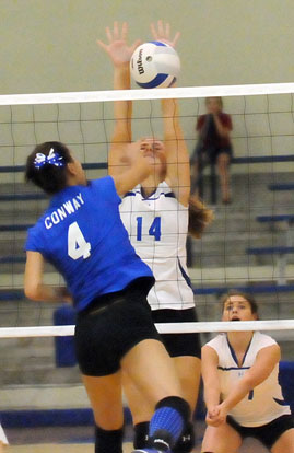 Riley Hill (14) reaches high for a block. (Photo by Kevin Nagle)
