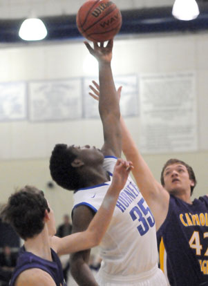 John Winston goes high for a rebound between two Catholic players. (Photo by Kevin Nagle)
