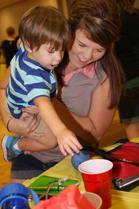 Two-year-old Ayden Martin drops a ticket into the auction cup with the help of his aunt, Kianna Ellithorpe. (Photo by Rick Nation)