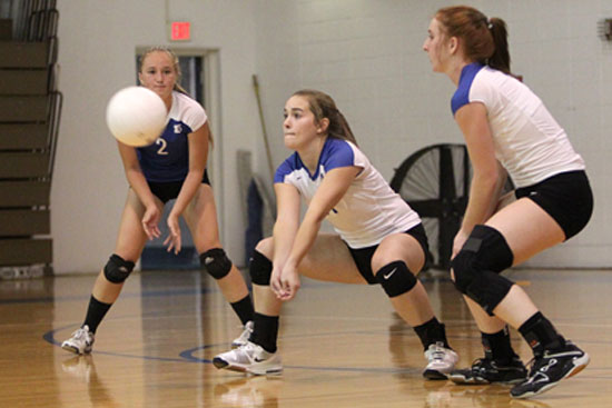 Abby Staton digs up a hit, flanked by Whitney Brown (2) and Nikki Clay (3). (Photo by Rick Nation)