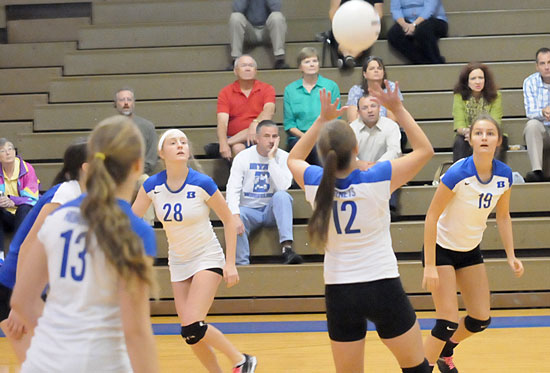 Sarah Kennedy (12) sets the ball for teammate Shaelyn Smith (19) as Reagan Blend (28) gets in position. (Photo by Kevin Nagle)