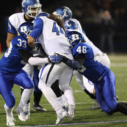 Hunter Fugitt (33) and Connor Chapdelaine (48) latch onto Conway's Kevin Chamorro (44). (Photo by Rick Nation)