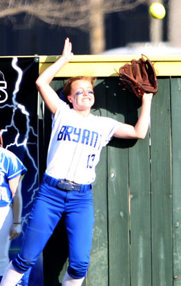 Bryant left fielder Regan Ryan hits her head on the fence as she tries to track down the home run hit by Conway's Kaylee St. John. (Photo by Rick Nation)