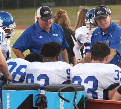 Coaches Brad Stroud, left, and Steve Griffith talk to the defense on the Bryant bench. (Photo by Rick Nation)