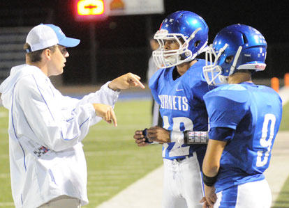 Bryant offensive coordinator Travis Queck instructs Hornets Josh Robinson (42) and Jake Self (9). (Photo by Kevin Nagle)