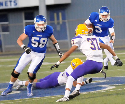 Senior quarterback Gunnar Burks leaps over a defender as he picks up a block from Cole Chapman (58) during Friday's game. (Photo by Kevin Nagle)