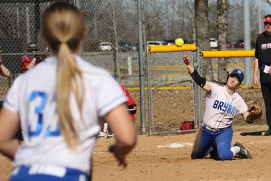 Shayla McKissock throws to Mallory Theel (33) at first from her knees after making a diving stop at third. (Photo by Rick Nation)