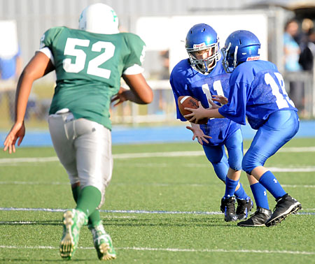 Quarterback Tyler Hesley (19) hands off to running back Austin Williams (11) as Pulaski Heights defender K.J. Dickerson approaches. (Photo by Kevin Nagle)