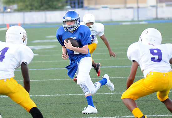 Bryant White quarterback Aiden Adams looks for running room between two Horace Mann defenders, Shajuan Esteen (4) and Keilon Davis (9). (Photo by Kevin Nagle)