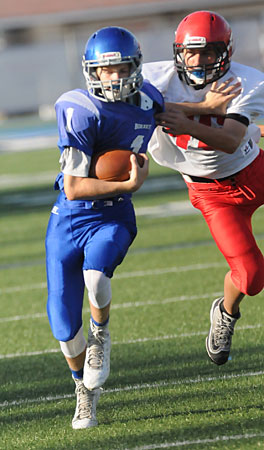 Bethel quarterback Garrett Wilson (1) uses a stiff arm to try to get past Cabot Red's Cody McCoy. (Photo by Kevin Nagle)