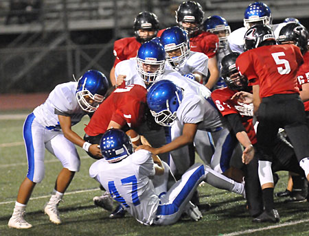 Bryant's defense envelopes Russellville running back Cole Heathcote as Ryan Riedmueller (47) tries the pry the ball loose. (Photo by Kevin Nagle)